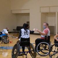 Teammates fist bumping in a wheelchair floor hockey game.